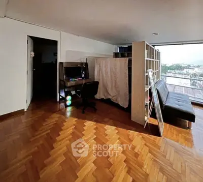 Spacious living area with parquet flooring and city view, featuring a cozy workspace and modern furnishings.