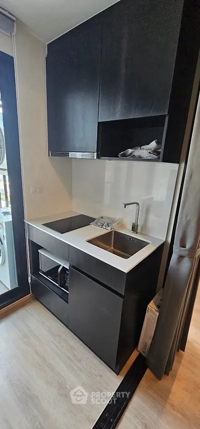 Modern compact kitchen with sleek black cabinetry and built-in appliances