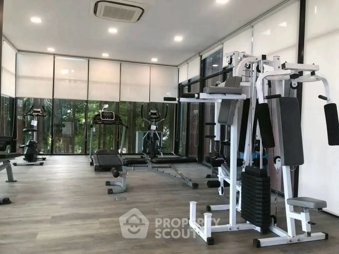 Modern gym with state-of-the-art fitness equipment and large windows offering a serene view.