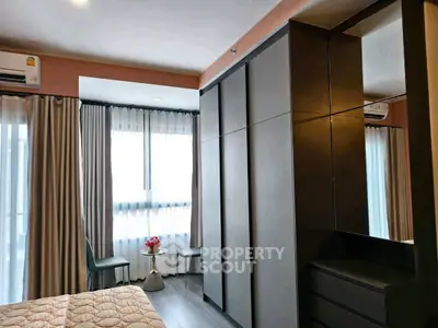 Modern bedroom with large wardrobe and cozy seating area by the window.