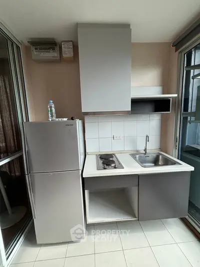 Compact kitchen with stainless steel fridge and electric stove in modern apartment