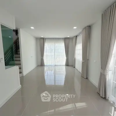 Spacious modern living room with large windows and elegant curtains