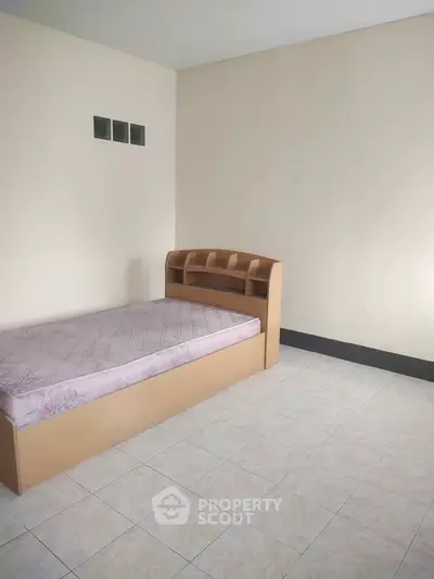 Minimalist bedroom with single bed and tiled floor, perfect for cozy living.