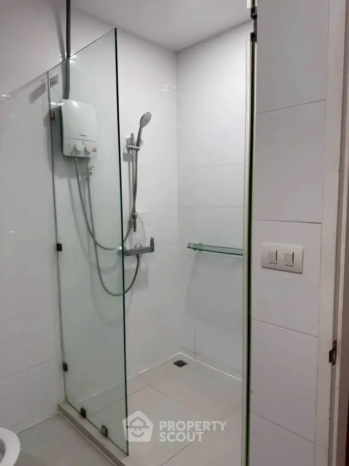 Modern bathroom with glass shower enclosure and sleek white tiles.