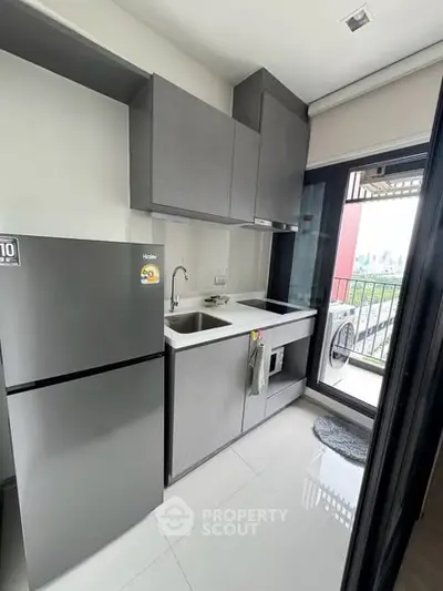 Modern kitchen with sleek cabinetry and balcony view in urban apartment