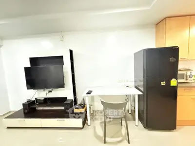Modern living space with TV, fridge, and dining area in open layout.