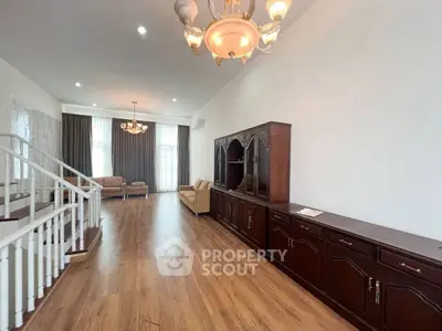 Spacious living room with elegant wooden flooring and classic furniture, ideal for family gatherings.