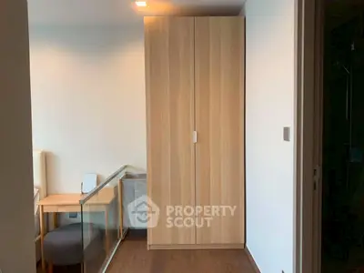 Modern interior with wooden wardrobe and cozy seating area, perfect for compact living spaces.