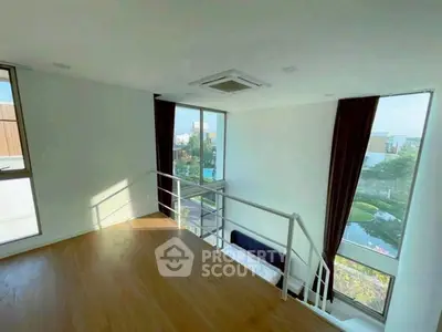 Spacious modern living room with large windows and scenic view, featuring sleek wooden flooring and elegant staircase.