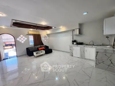 Spacious living room with modern open kitchen and stylish marble flooring.
