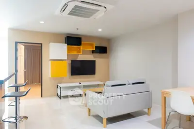 Modern living room with stylish furniture and wall-mounted TV, featuring a sleek air conditioning unit.