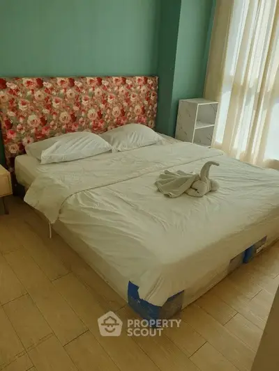 Cozy bedroom with floral headboard and natural light, perfect for relaxation.