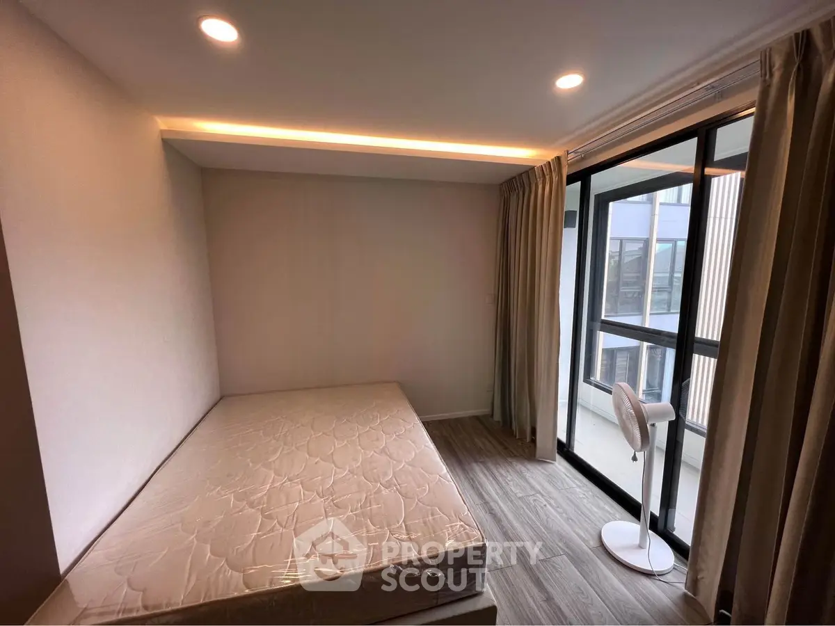 Modern bedroom with large windows and natural light, featuring a minimalist design and cozy atmosphere.