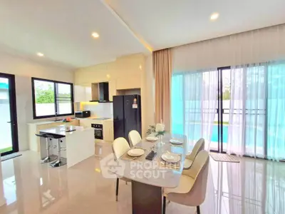 Modern open-layout kitchen and dining area with pool view, featuring sleek appliances and elegant decor.