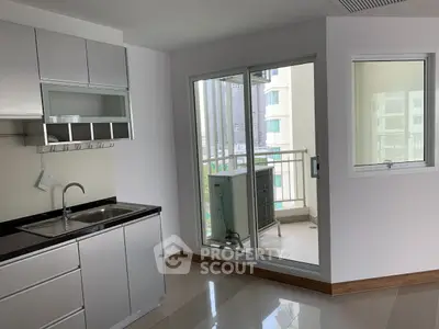 Modern kitchen with sleek cabinetry and access to a small balcony in a bright apartment.