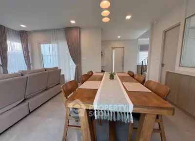 Spacious modern dining area with elegant wooden table and cozy living room setup.