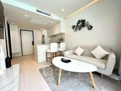Modern living room with open kitchen, stylish decor, and cozy seating area.