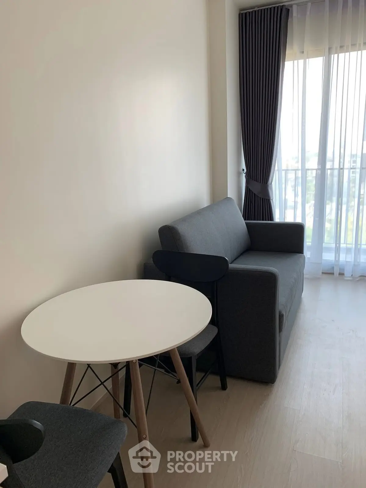 Modern living room with sleek furniture and natural light from large window.