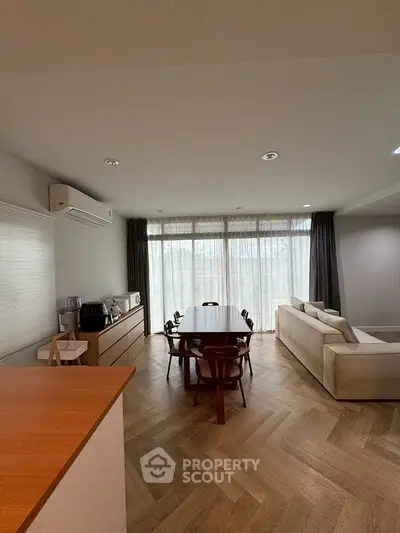 Spacious modern living room with elegant dining area and natural light.