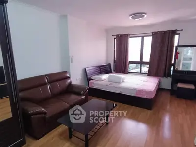 Spacious studio apartment with modern furnishings and large windows.