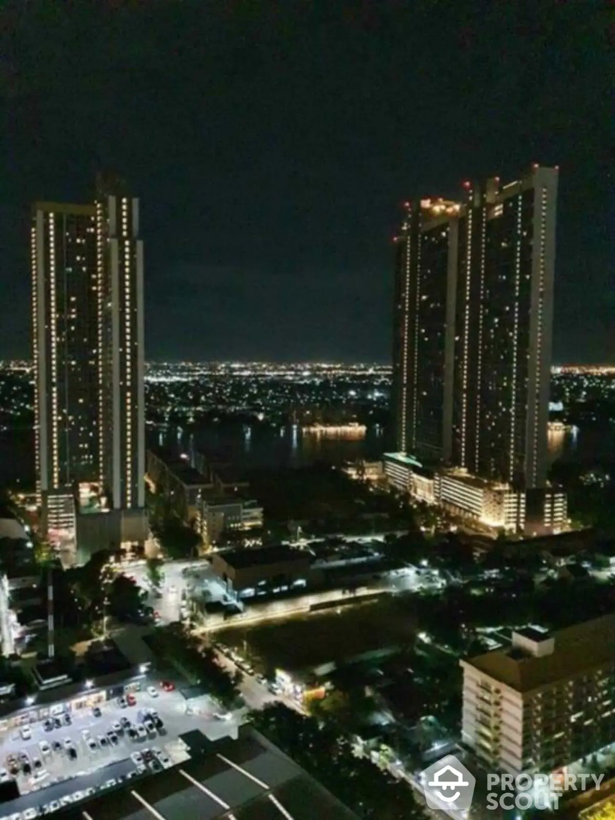 Stunning night view of high-rise buildings with city lights and river backdrop.