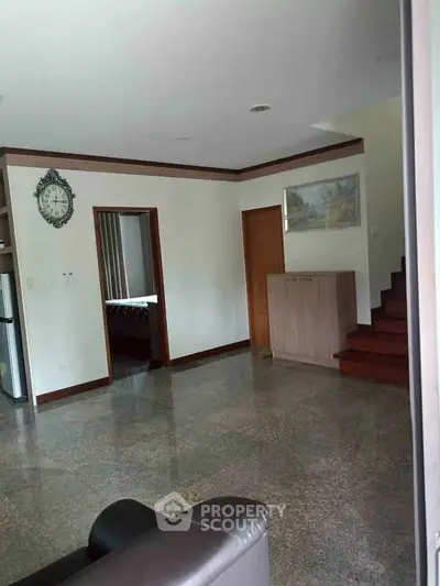 Spacious living room with elegant flooring and staircase, ideal for modern living.