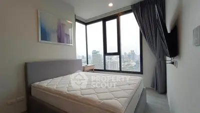 Modern bedroom with large windows offering stunning city views, featuring a comfortable bed and stylish decor.