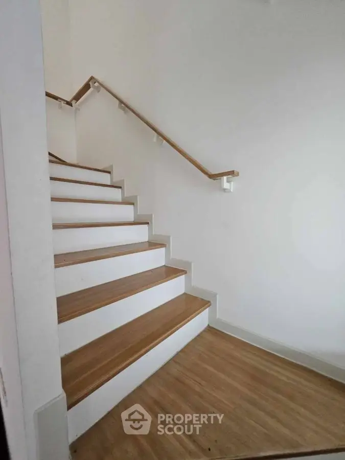 Modern wooden staircase with sleek handrail in minimalist home interior