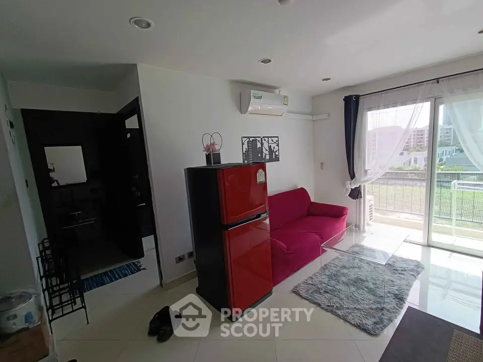Modern living room with red sofa, air conditioning, and balcony view in a bright apartment.