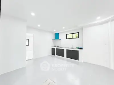 Modern minimalist kitchen with sleek black and white design, featuring gas stove and ample natural light.