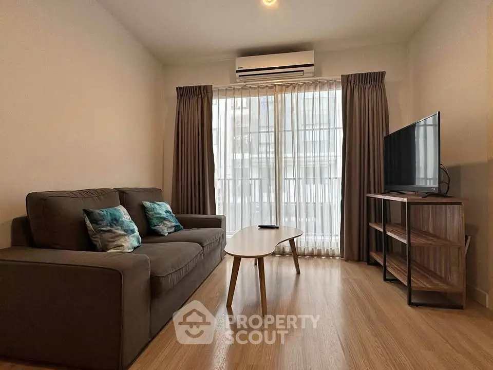 Modern living room with cozy sofa, TV, and natural light from large window.