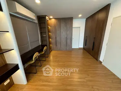 Spacious study room with modern wooden flooring and built-in shelves, perfect for productivity.