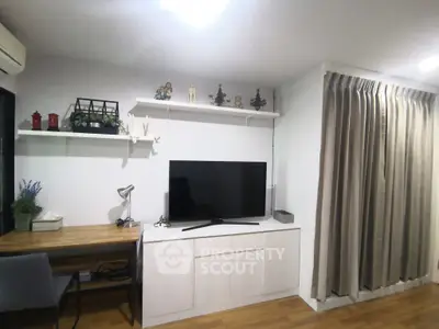 Modern living room with TV, desk, and decorative shelves in cozy apartment.