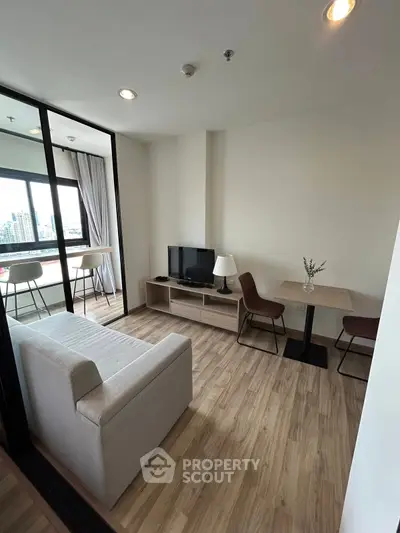 Modern living room with city view, cozy seating, and stylish decor in a high-rise apartment.