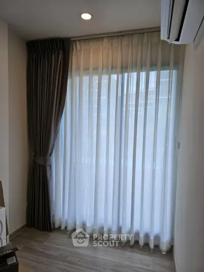 Modern room with elegant floor-to-ceiling curtains and air conditioning, showcasing a serene ambiance.