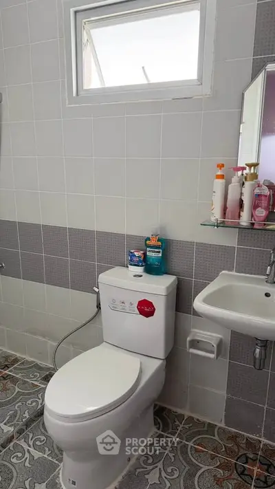 Modern bathroom with tiled walls, compact sink, and window for natural light.
