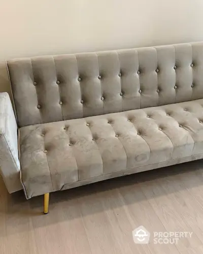 Elegant tufted grey sofa with plush upholstery and chic yellow legs, adding a touch of sophistication to any modern living space.