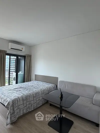 Modern bedroom with bed, sofa, and balcony view in a stylish apartment.