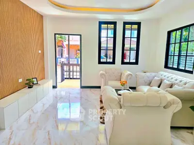 Elegant living room with plush white sofas and large windows, offering a bright and inviting atmosphere.
