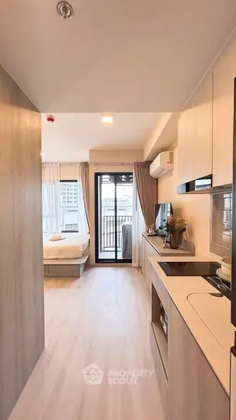 Modern studio apartment with open kitchen and balcony view, featuring sleek design and natural light.