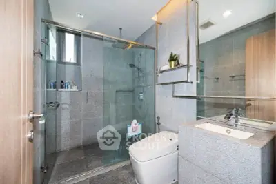 Modern bathroom with glass shower and sleek fixtures in luxury apartment.