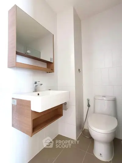 Modern bathroom with sleek fixtures and wooden accents, featuring a wall-mounted sink and toilet.