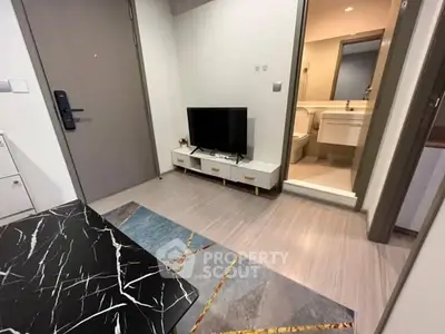 Modern apartment interior with TV and marble table, adjacent to a bathroom.