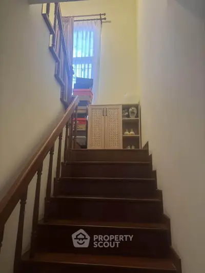 Charming staircase with wooden railing and storage cabinet, perfect for cozy home ambiance.