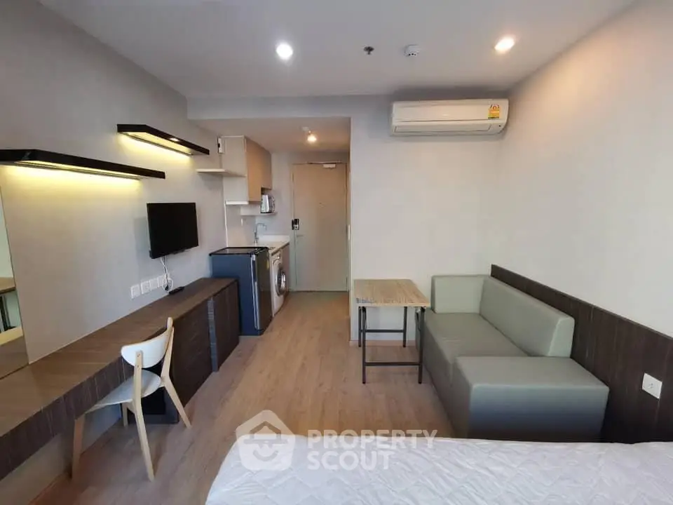 Modern studio apartment with sleek furniture and compact kitchen area