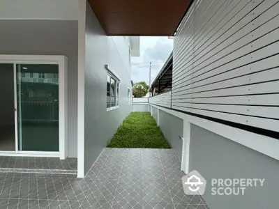 Modern side yard with tiled patio and sliding glass doors in contemporary home