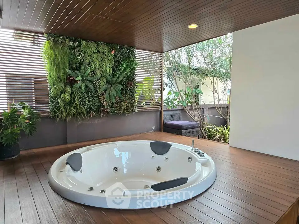 Luxurious outdoor jacuzzi with wooden deck and lush vertical garden for ultimate relaxation.