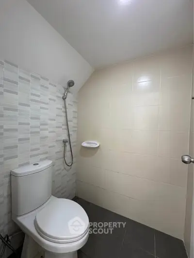 Modern bathroom with sleek tiles and shower area in a minimalist design.