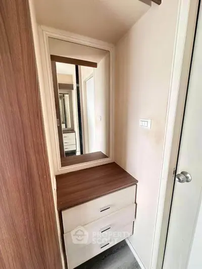 Compact bedroom corner with mirror and wooden drawers, perfect for storage.