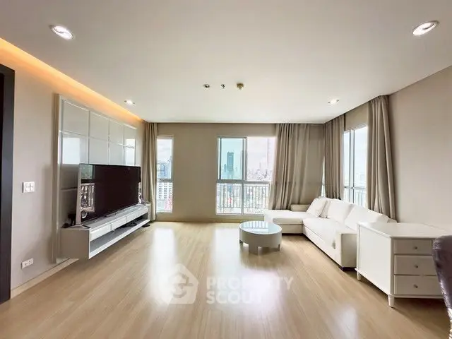 Spacious modern living room with large windows and city view, featuring sleek furniture and wooden flooring.